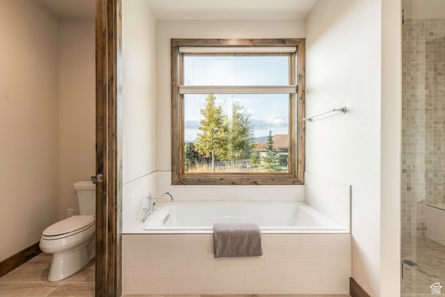 bathroom featuring a relaxing tiled tub and toilet