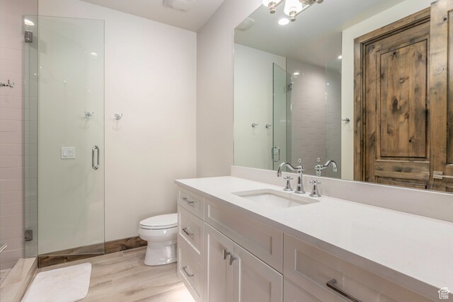 bathroom featuring a shower with door, vanity, hardwood / wood-style flooring, and toilet