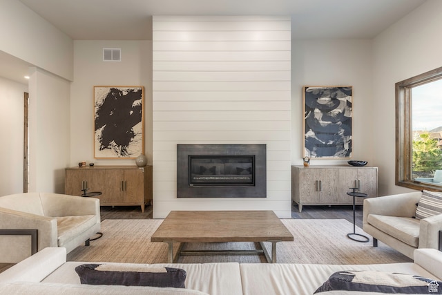 living room with a large fireplace and hardwood / wood-style flooring