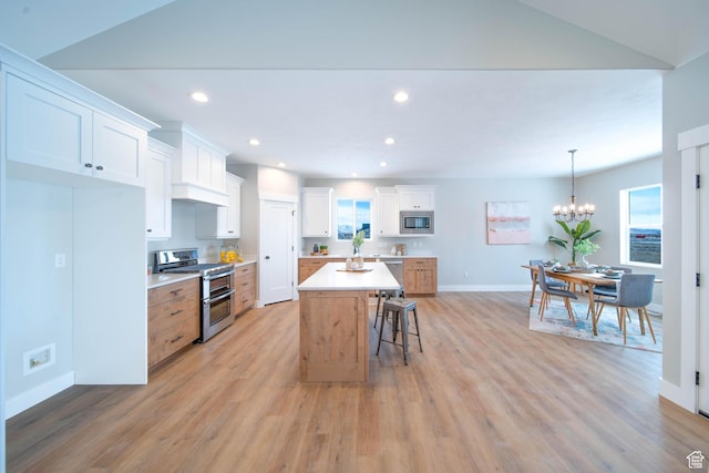 kitchen with appliances with stainless steel finishes, light hardwood / wood-style flooring, white cabinetry, and a center island