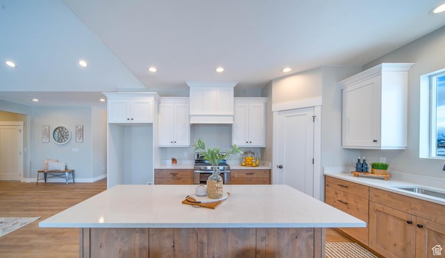 kitchen with sink, a kitchen island, white cabinetry, and stainless steel range oven