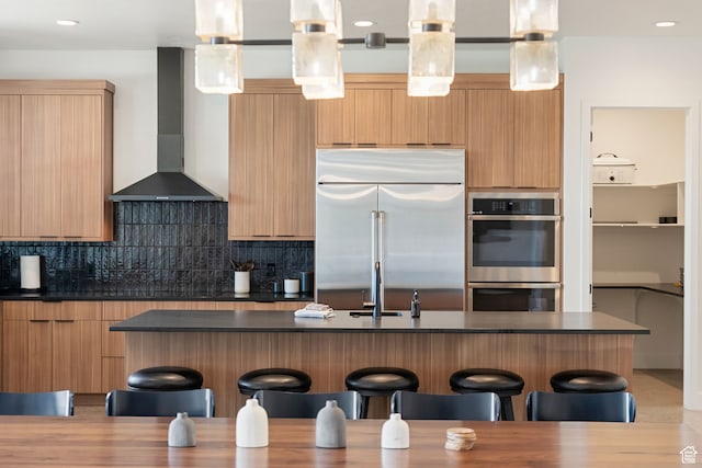 70 W 350 S, Garden City, UT 84028 - kitchen featuring tasteful backsplash, wall chimney range hood, appliances with stainless steel finishes, pendant lighting, and a breakfast bar area