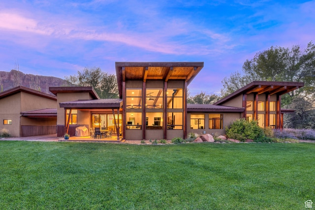 425 Amber Ln, Castle Valley, UT 84532 - back house at dusk with a patio area and a lawn