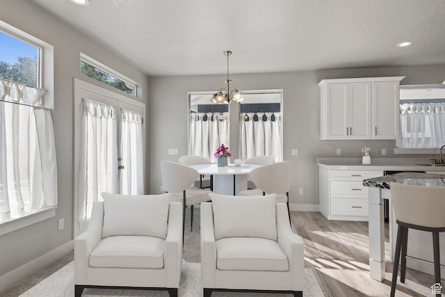 dining space with baseboards, a chandelier, light wood finished floors, and recessed lighting