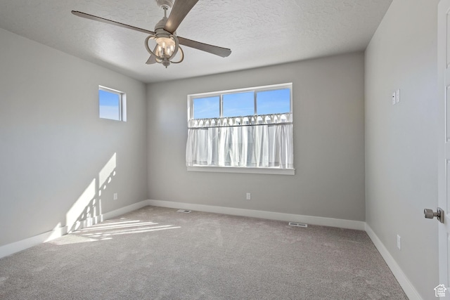 unfurnished room featuring carpet, visible vents, a ceiling fan, baseboards, and a textured ceiling