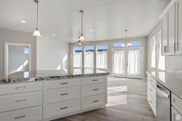 kitchen with white cabinets, french doors, stainless steel dishwasher, light wood-style flooring, and decorative light fixtures