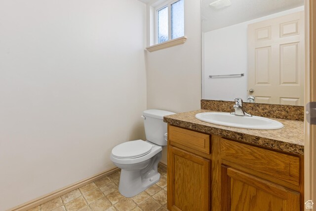 bathroom with toilet, vanity, and baseboards