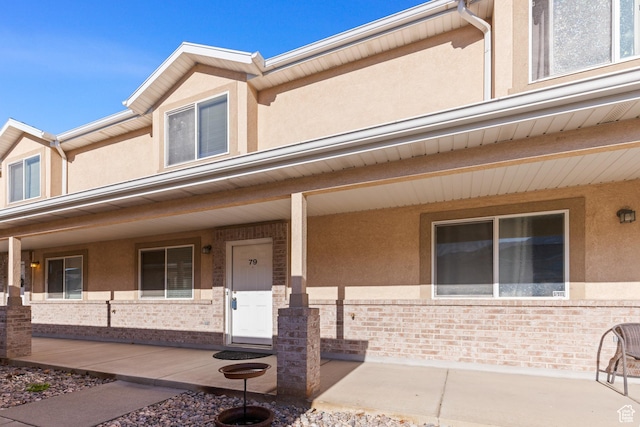 townhome / multi-family property with stucco siding, brick siding, and a porch