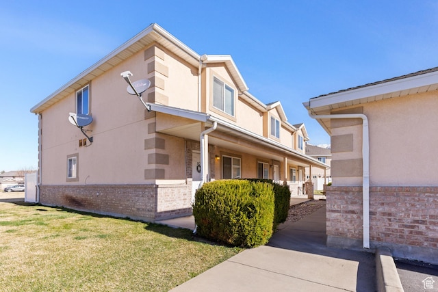view of property exterior featuring brick siding, stucco siding, and a yard