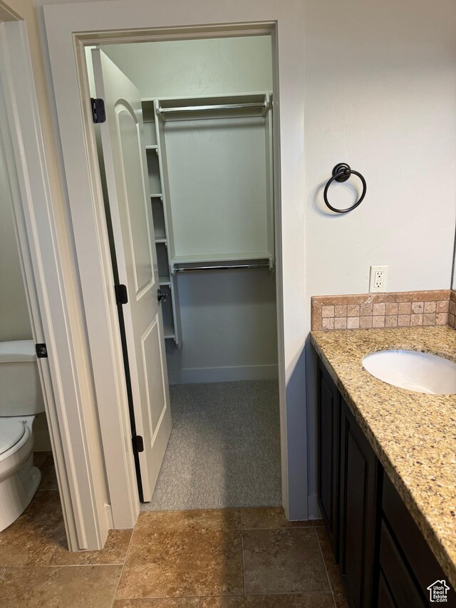 1260 N 200 W, Bountiful, UT 84010 - bathroom featuring stone finish floor, a walk in closet, vanity, baseboards, and toilet