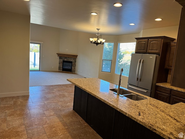 1260 N 200 W, Bountiful, UT 84010 - kitchen featuring light stone countertops, a sink, a tiled fireplace, freestanding refrigerator, and baseboards