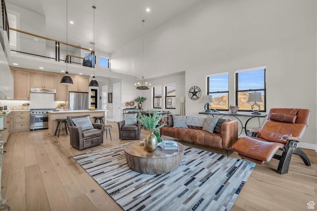 living room featuring light wood finished floors, a high ceiling, recessed lighting, and a chandelier