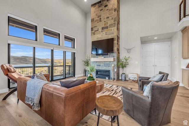 living room featuring a towering ceiling, light wood finished floors, baseboards, and a fireplace