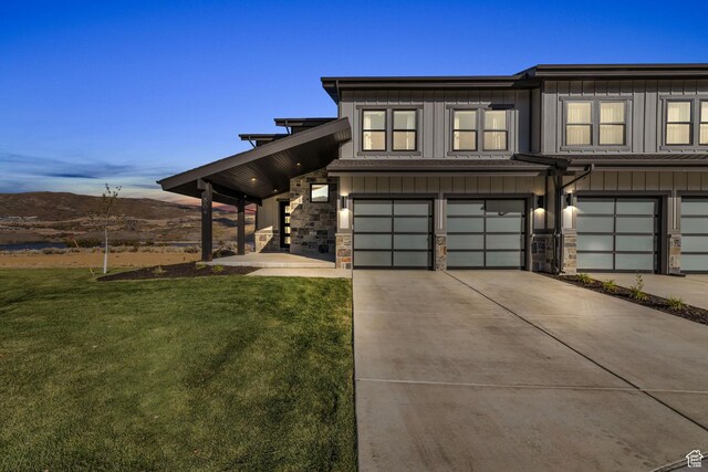 multi unit property with driveway, board and batten siding, stone siding, a front yard, and a garage