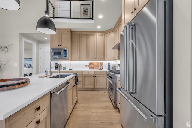 kitchen featuring light wood finished floors, a sink, stainless steel appliances, light brown cabinets, and light countertops