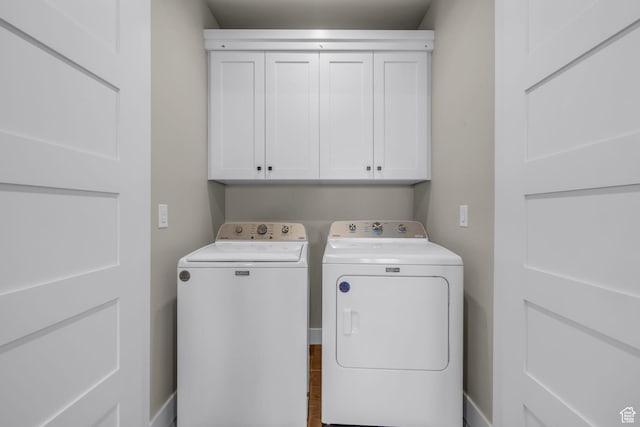 clothes washing area with washing machine and dryer and cabinet space
