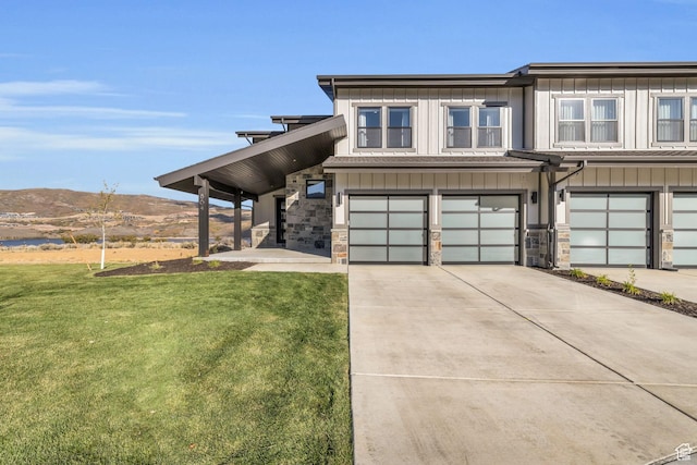 townhome / multi-family property featuring a garage, board and batten siding, a front lawn, and driveway
