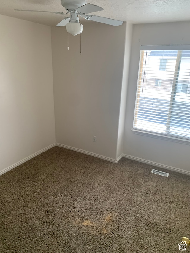 carpeted spare room featuring a textured ceiling and ceiling fan