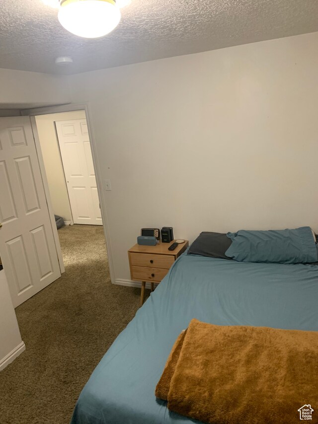 bedroom featuring a textured ceiling and dark carpet