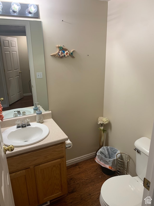 bathroom with toilet, vanity, and wood-type flooring