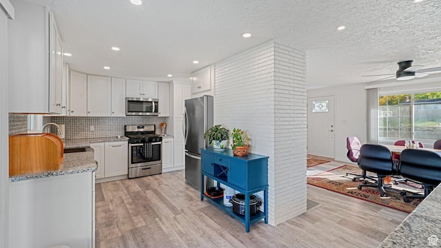 535 N 300 E, Brigham City, UT 84302 - kitchen with light stone counters, white cabinets, stainless steel appliances, and light wood-type flooring