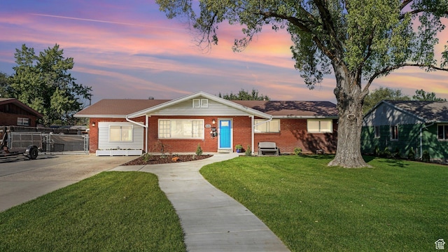 535 N 300 E, Brigham City, UT 84302 - view of front facade featuring brick siding, driveway, fence, and a front lawn