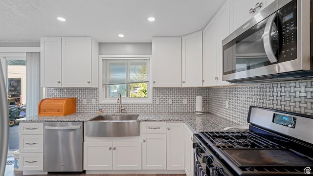 535 N 300 E, Brigham City, UT 84302 - kitchen with white cabinets, tasteful backsplash, light stone counters, a sink, and stainless steel appliances