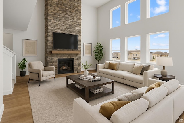 living area with baseboards, light wood-type flooring, and a towering ceiling