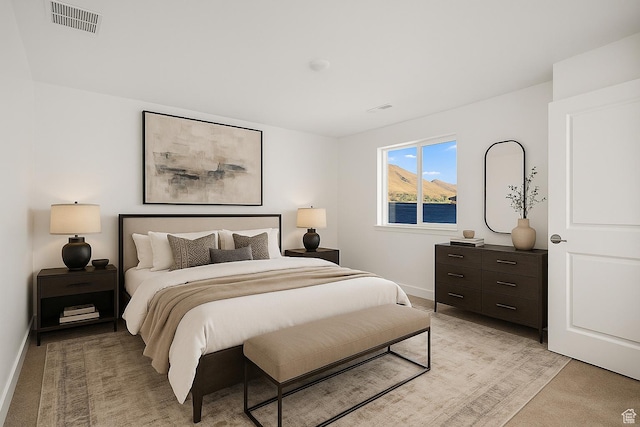 bedroom featuring baseboards, visible vents, and light carpet