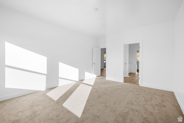 spare room featuring baseboards and light carpet