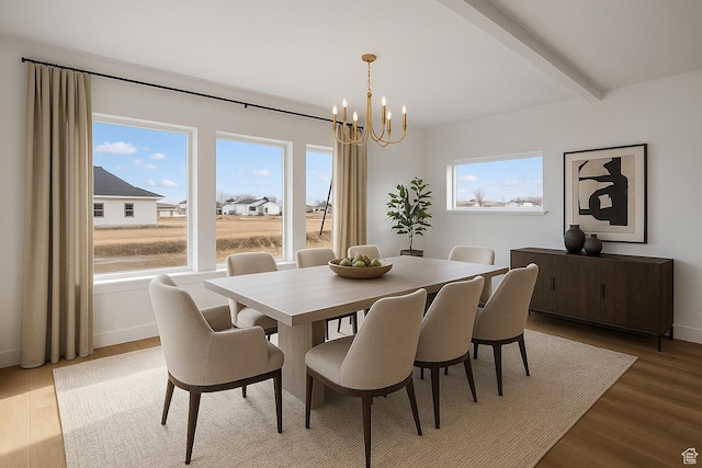 dining area with beamed ceiling, a chandelier, a healthy amount of sunlight, and wood finished floors