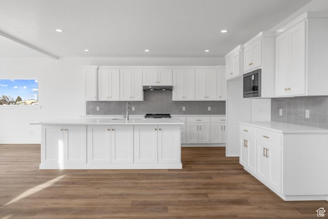 kitchen featuring under cabinet range hood, white cabinetry, black microwave, and light countertops