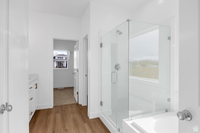 full bathroom with a bath, a shower stall, wood finished floors, vanity, and baseboards