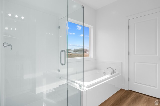 bathroom with a shower stall, wood finished floors, and a bath