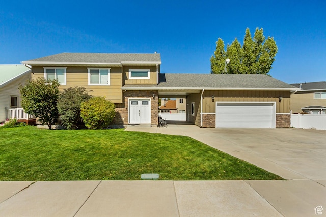 tri-level home with a front lawn, driveway, stone siding, an attached garage, and board and batten siding