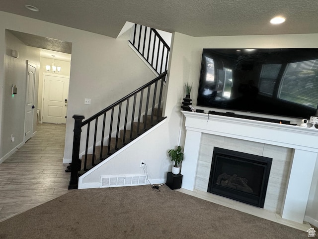 living room featuring a fireplace, visible vents, a textured ceiling, and stairway