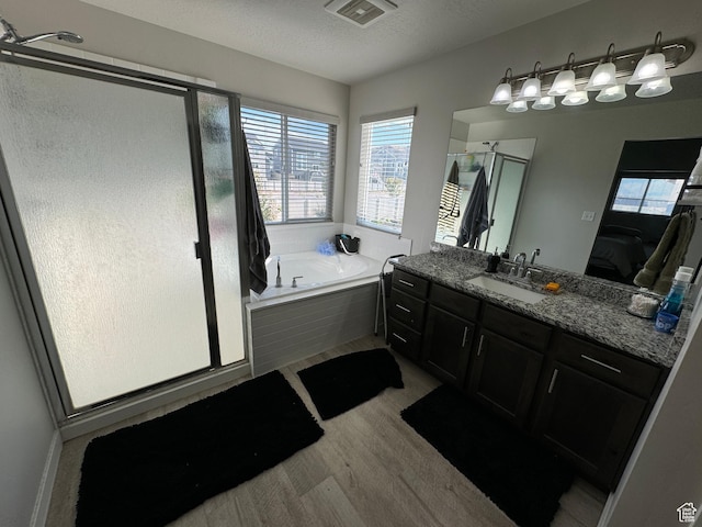 ensuite bathroom featuring a bath, a shower stall, visible vents, and vanity