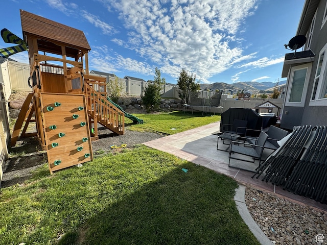 view of yard featuring a fenced backyard, a mountain view, a playground, a trampoline, and a patio area