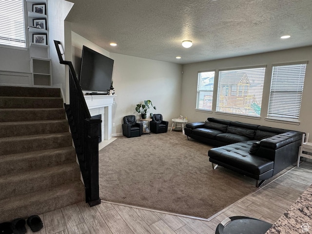 living area featuring a fireplace with flush hearth, wood finished floors, a textured ceiling, and stairway