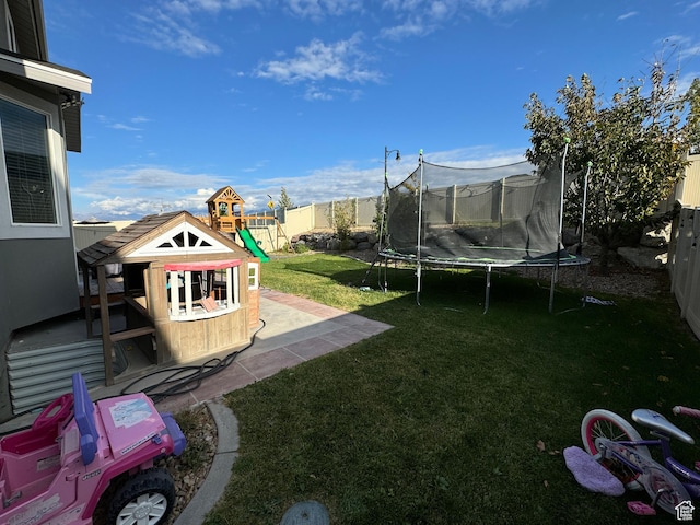 view of yard featuring a trampoline, a patio, a fenced backyard, and a playground