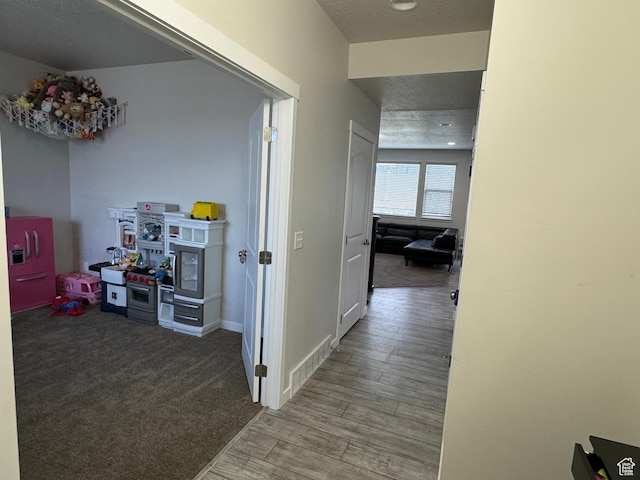 hallway with baseboards, wood finished floors, and visible vents