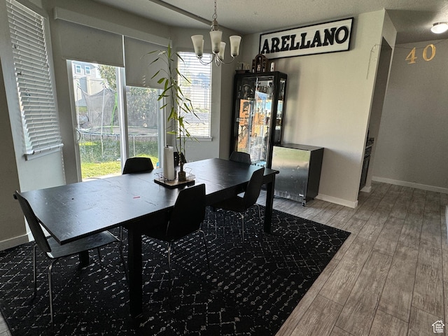 dining space featuring an inviting chandelier, wood finished floors, and baseboards