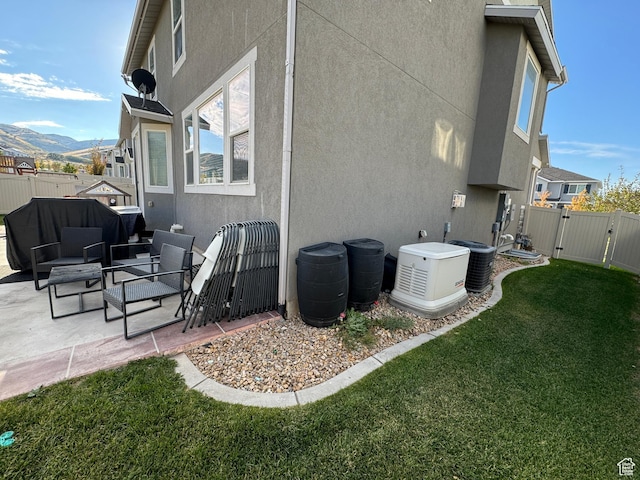 back of property with a gate, a patio area, a lawn, and stucco siding
