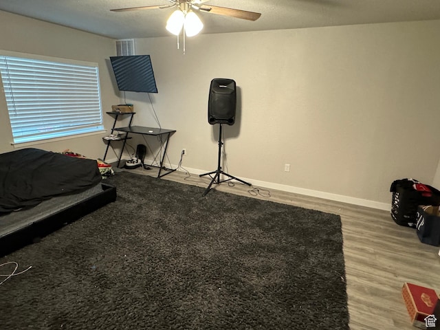 bedroom featuring visible vents, baseboards, a ceiling fan, and wood finished floors