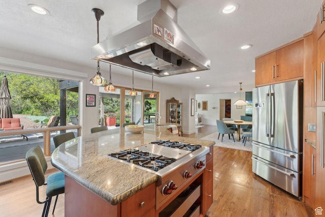 3797 Blacksmith Rd, Park City, UT 84098 - kitchen featuring appliances with stainless steel finishes, island exhaust hood, brown cabinetry, light wood finished floors, and light stone countertops