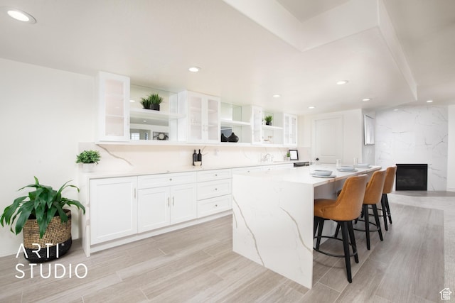 14714 S Pristine Dr E, Draper, UT 84020 - kitchen with open shelves, a breakfast bar area, light wood-style flooring, white cabinetry, and glass insert cabinets