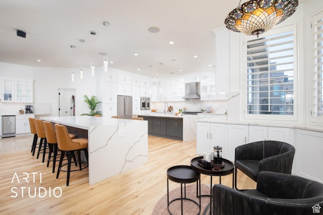 14714 S Pristine Dr E, Draper, UT 84020 - kitchen featuring a large island, appliances with stainless steel finishes, light wood finished floors, and wall chimney exhaust hood
