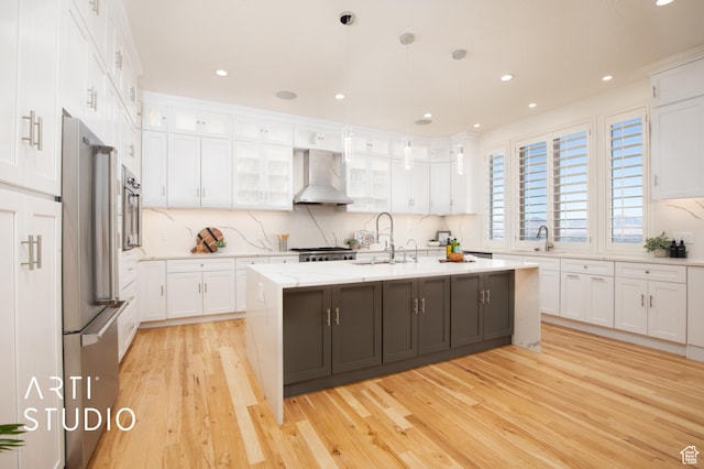 14714 S Pristine Dr E, Draper, UT 84020 - kitchen with light wood-style floors, a sink, white cabinets, and wall chimney range hood
