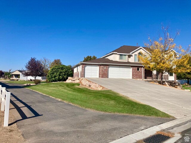 5046 W 4250 S, West Haven, UT 84401 - view of front of property featuring brick siding, concrete driveway, a garage, a residential view, and a front lawn