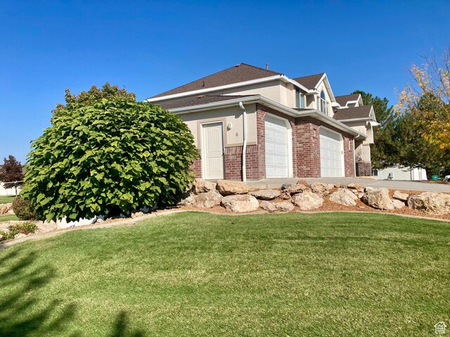 5046 W 4250 S, West Haven, UT 84401 - view of property exterior with a garage, a yard, stucco siding, and brick siding